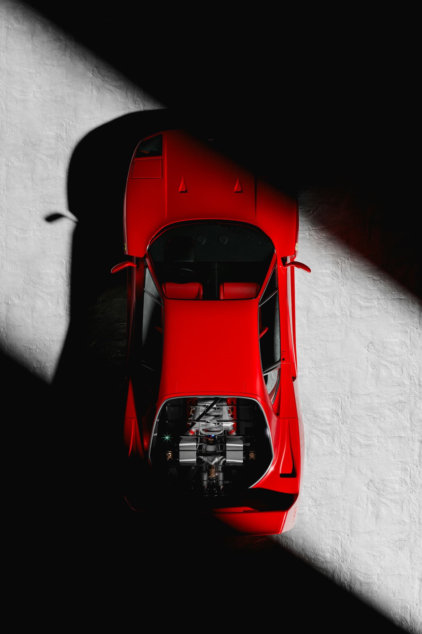 Overhead view of a red supercar split by a diagonal shaft of light